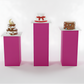Three small cakes on pink stands against a white background