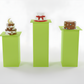 Three small cakes on green stands with a white background